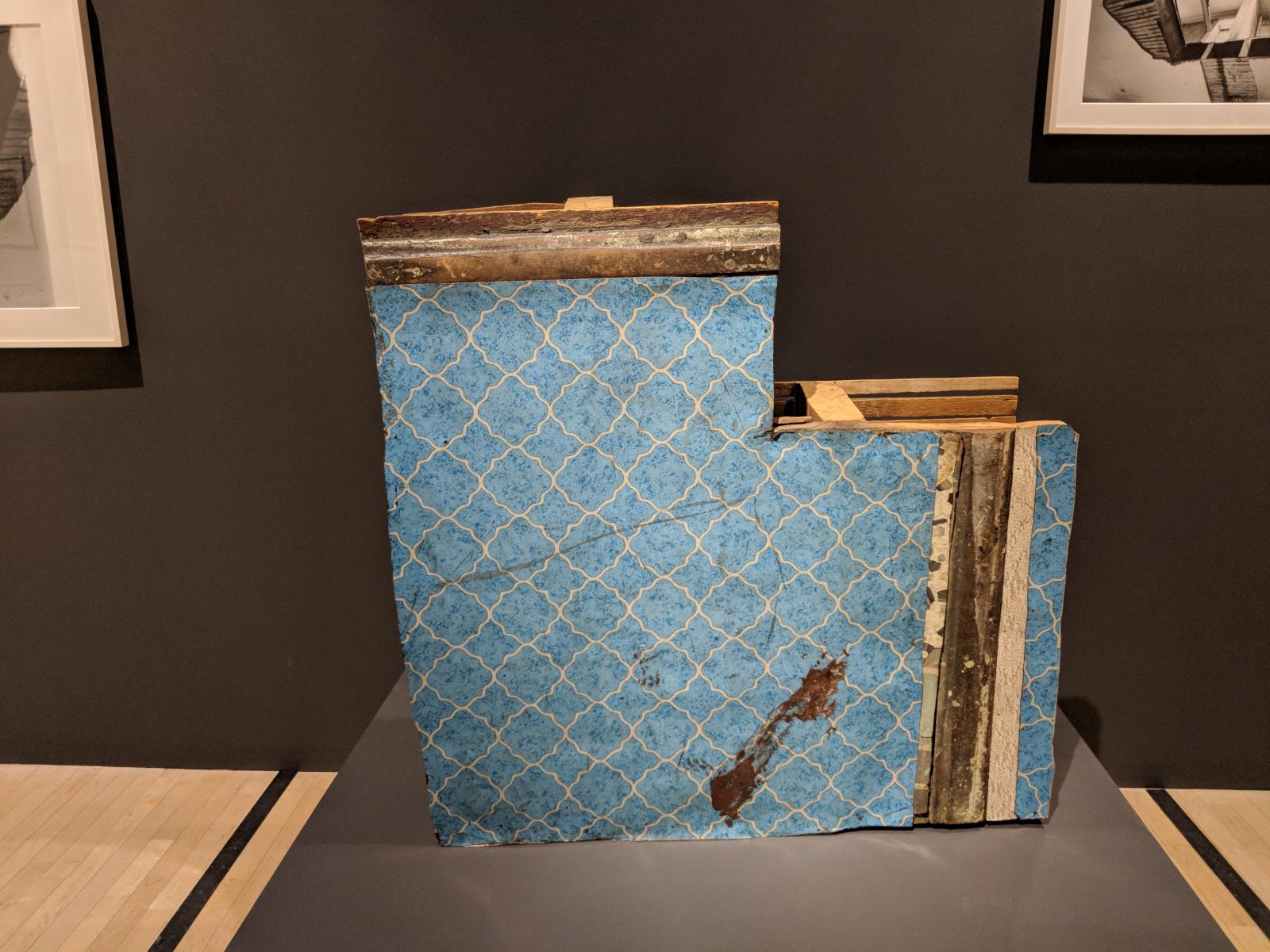 L-shaped piece of wall that has been removed from an actual apartment, showing the wooden beam structure that makes up the interior of the wall.